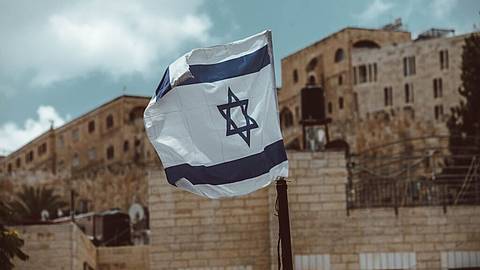 photo of the flag of Israel flapping in the wind in front of a housing compound